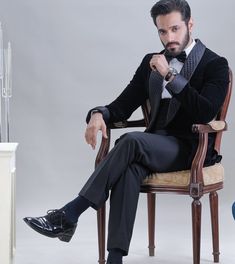 a man in a tuxedo sitting on a chair