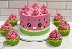 a cake with pink frosting and lots of cupcakes