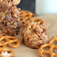 some cookies and pretzels are stacked on top of each other in front of a glass of milk