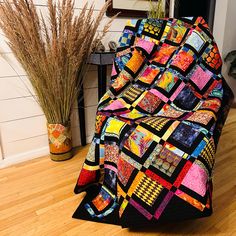 there is a large quilt on the floor next to a potted plant and vase