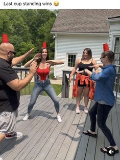 a group of people standing on top of a wooden deck next to each other in front of a house