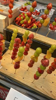 several skewers of fruit are on sticks in the shape of strawberries and grapes