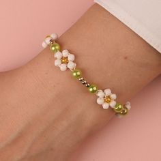 a woman's arm with a bracelet made out of beads and flowers on it