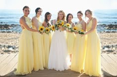 a group of women standing next to each other on top of a wooden floor near the ocean