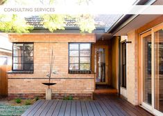 a wooden deck in front of a brick house