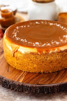 a cheesecake covered in caramel sauce on a wooden plate