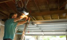 a man is working on an overhead light fixture in a garage with his ladder up to the ceiling