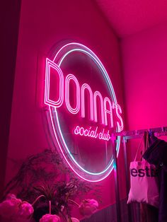 a neon sign that says dona's social club in front of a pink wall