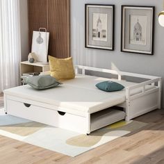 a white day bed with storage underneath it in a living room next to two pictures on the wall