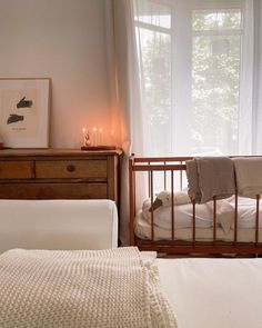 a baby crib in front of a window with candles on the windowsills