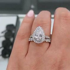 a woman's hand with a diamond ring on top of her finger and the other hand holding an engagement ring