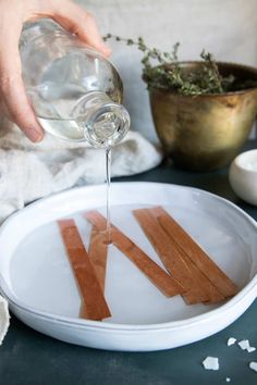 someone pouring water into a plate with strips of wood