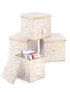 three white boxes stacked on top of each other with gold trimmings and designs