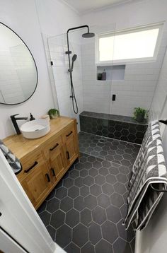 a bathroom with hexagonal tile and wooden cabinetry, along with a round mirror on the wall