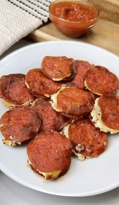 a white plate topped with mini pizzas next to a bowl of ketchup