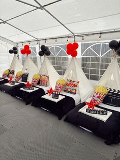 a row of tents with black and white decorations on them in a room filled with balloons