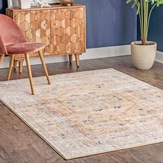 an area rug in the corner of a room with two chairs and a potted plant