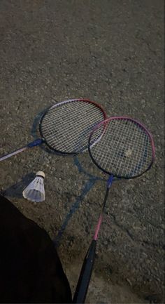 two tennis racquets laying on the ground next to each other with strings attached