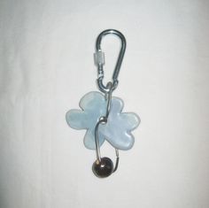 a key chain with a flower shaped glass object hanging from it's side on a white surface