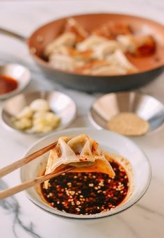 some food is being served in bowls with chopsticks on the side and another bowl behind it