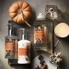 an assortment of hand and body care products on a table with candles, pumpkins, cinnamon spicers, soap