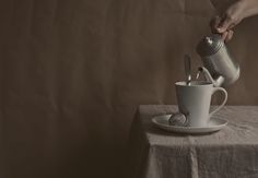 a person pouring something into a cup on top of a white saucer and plate