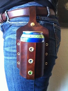 a person wearing jeans and holding a brown leather beer can holder with eyeballs on it