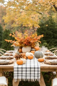 a table set with pumpkins and other autumn decorations