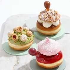 three donuts with different toppings on them sitting on plates next to each other