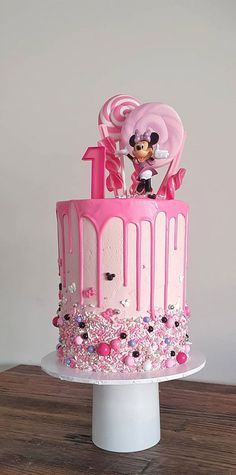 a minnie mouse cake with pink icing and sprinkles