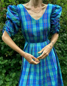 "Vintage 1980s plaid taffeta party dress with massive puff sleeves. The dress is a stunning blue, red, green and shimmering gold plaid taffeta and features a scoop-V neckline, fitted waist and elasticized pouf sleeves. It has a zipper closure at the back. Would fit a modern size xsmall to small - model is size 2 and 5'8 for reference - please see measurements below.  Belt in photo not included. Brand/Designer: House of Nu-Mode  Condition: very good vintage condition - very tiny pinhole mend at the back and under a pleat so you'd never notice when worn Measurements**measurements are taken seam to seam while garment is lying flat - double for bust, waist, hips:  shoulder to shoulder: 16\"  bust: 17.5\"    waist: 13\"  hip: 23\"  length: (shoulder to bottom hem): 42\"   bodice: 15.5\" Please Summer Plaid Puff Sleeve Dress, Vintage Multicolor Puff Sleeve Dress, Vintage Short Sleeve Plaid Cotton Dress, 1940s Plaid Dress, 80s Puff Sleeve Dress, Mum Fashion, Printed Shift Dress, Roll Up Sleeves, Silk Chiffon