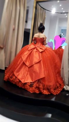 a woman in an orange ball gown looking at herself in the mirror with her reflection