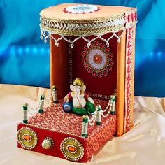 an elaborately decorated red and gold carton sitting on top of a white sheet