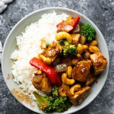 a white bowl filled with chicken and broccoli over rice on top of a table