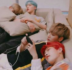 three boys laying on a couch with remotes in their hands and one boy is holding a game controller