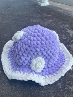 a purple and white crocheted hat sitting on top of a cement ground next to a building