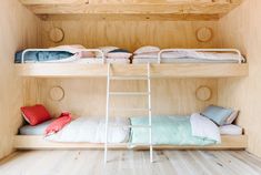 two bunk beds in a room with wooden walls and flooring, one is made from plywood