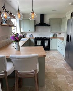 a kitchen with an island, stove and refrigerator in it's center area next to two chairs