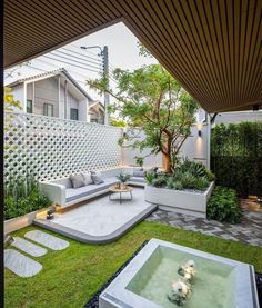 an outdoor living area with couches, tables and potted plants on the lawn