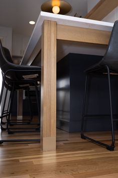 two black chairs sitting under a wooden table next to a counter top with stools