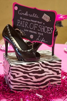 a pair of high heel shoes sitting on top of a zebra print box with pink tinsel