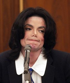 michael jackson speaking into a microphone in front of a wooden paneled wall and floor