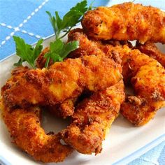 some fried food is on a white plate with parsley sprig and garnish