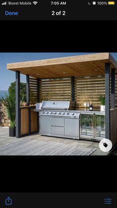 an outdoor kitchen with grill and sink under a roof over looking the ocean on a sunny day