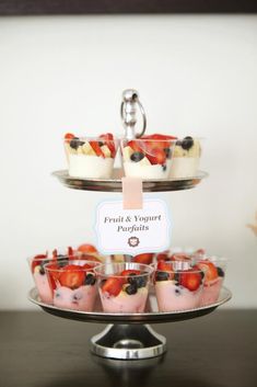 desserts are arranged on three tiered trays, each topped with fruit and yogurt