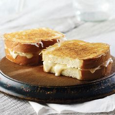 two grilled sandwiches sitting on top of a wooden plate