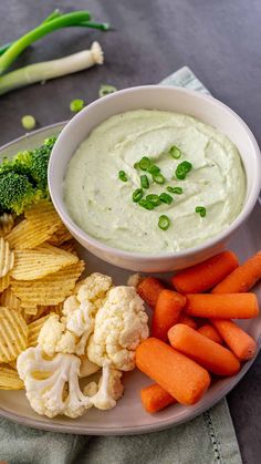 a white plate topped with carrots, cauliflower and crackers next to broccoli