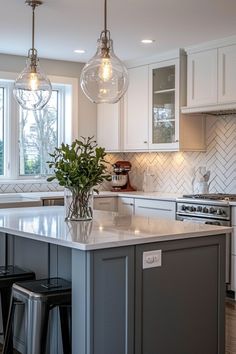 a kitchen island with two stools in front of it and three lights hanging from the ceiling