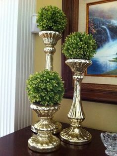 two gold vases with plants in them on a table