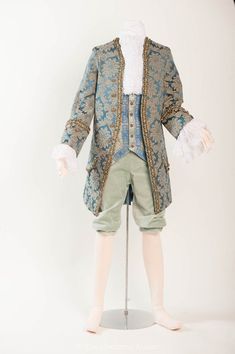 a mannequin wearing a blue and gold jacket with white lace on it's sleeves